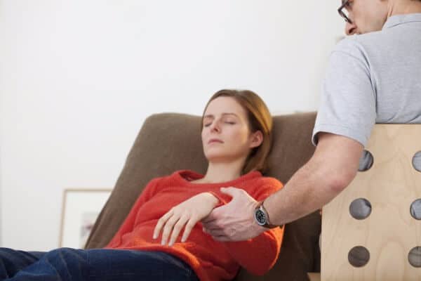 woman hypnotised by a rapid induction, the hypnotherapist holding her arm to test for depth