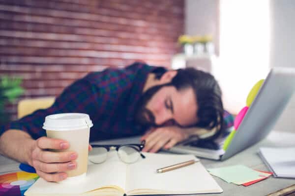 man tired working laptop coffee asleep workplace stress and wellbeing