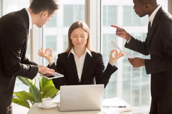 Woman using self-hypnosis at work to deal with stress, when colleagues are shouting at her.