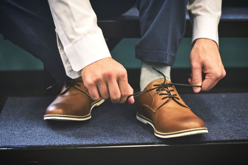 habits and changing behaviours - people have a habit of tying their shoe laces - image of a man with brown loafers and shoelaces being tied.