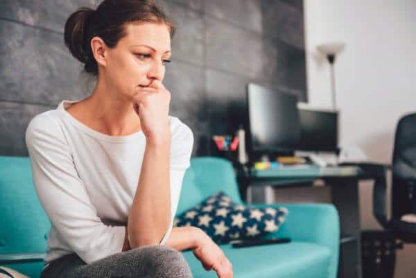 Woman on sofa engaging in negative mental rehearsal, looking really upset.